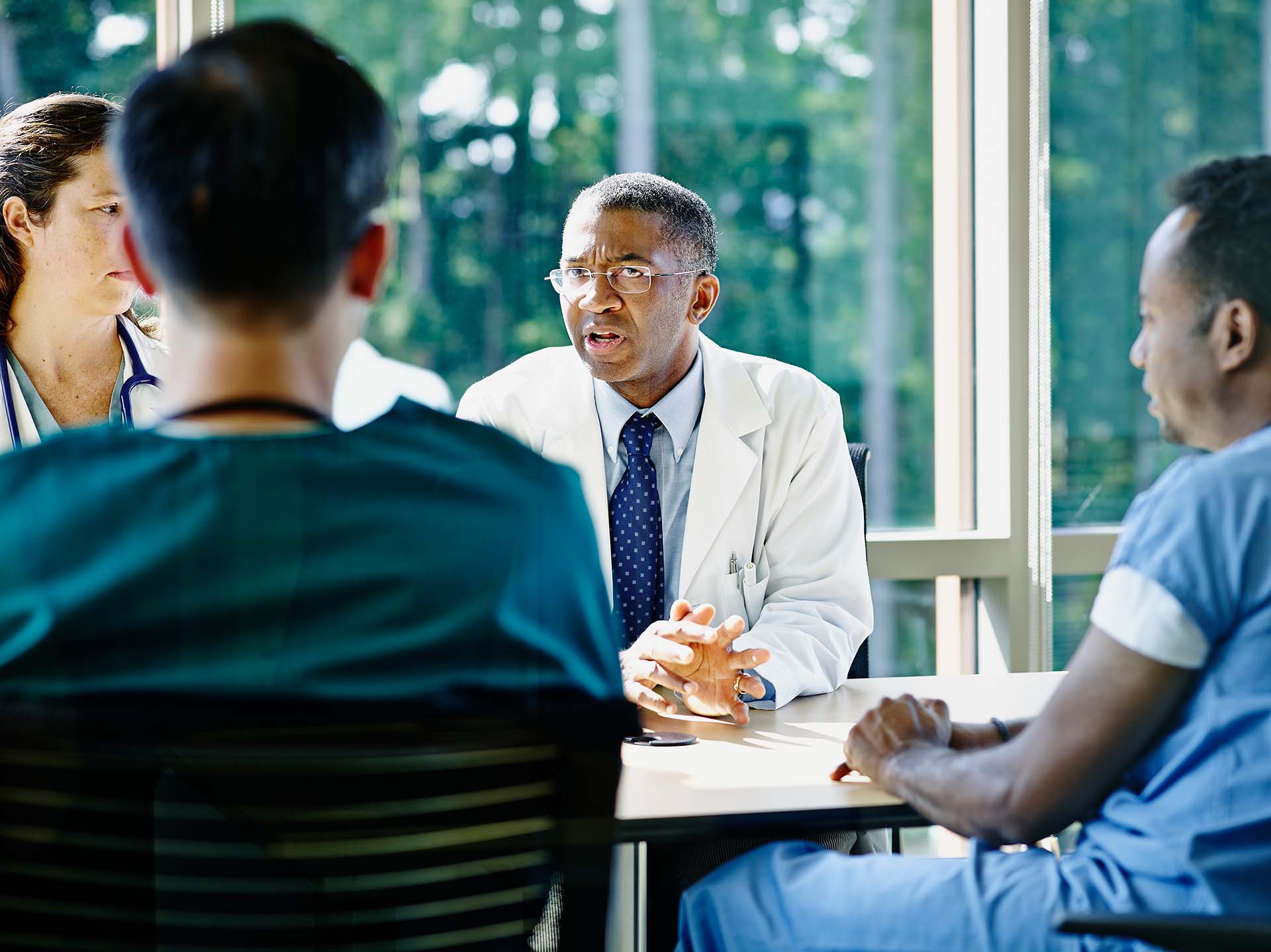 Mature Male Doctor Leading Medical Team Meeting Mature male doctor leading discussion in medical team meeting in conference room in hospital