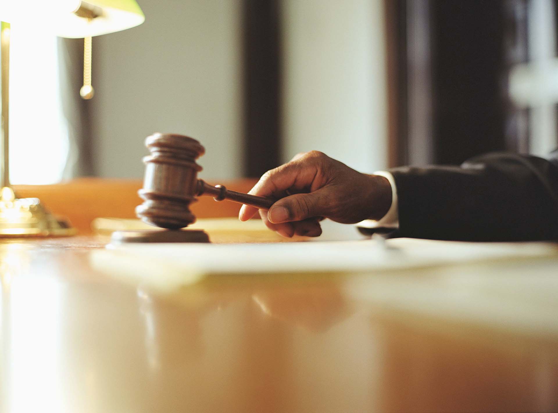 Male Judge Striking Gavel In Courtroom, Close Up