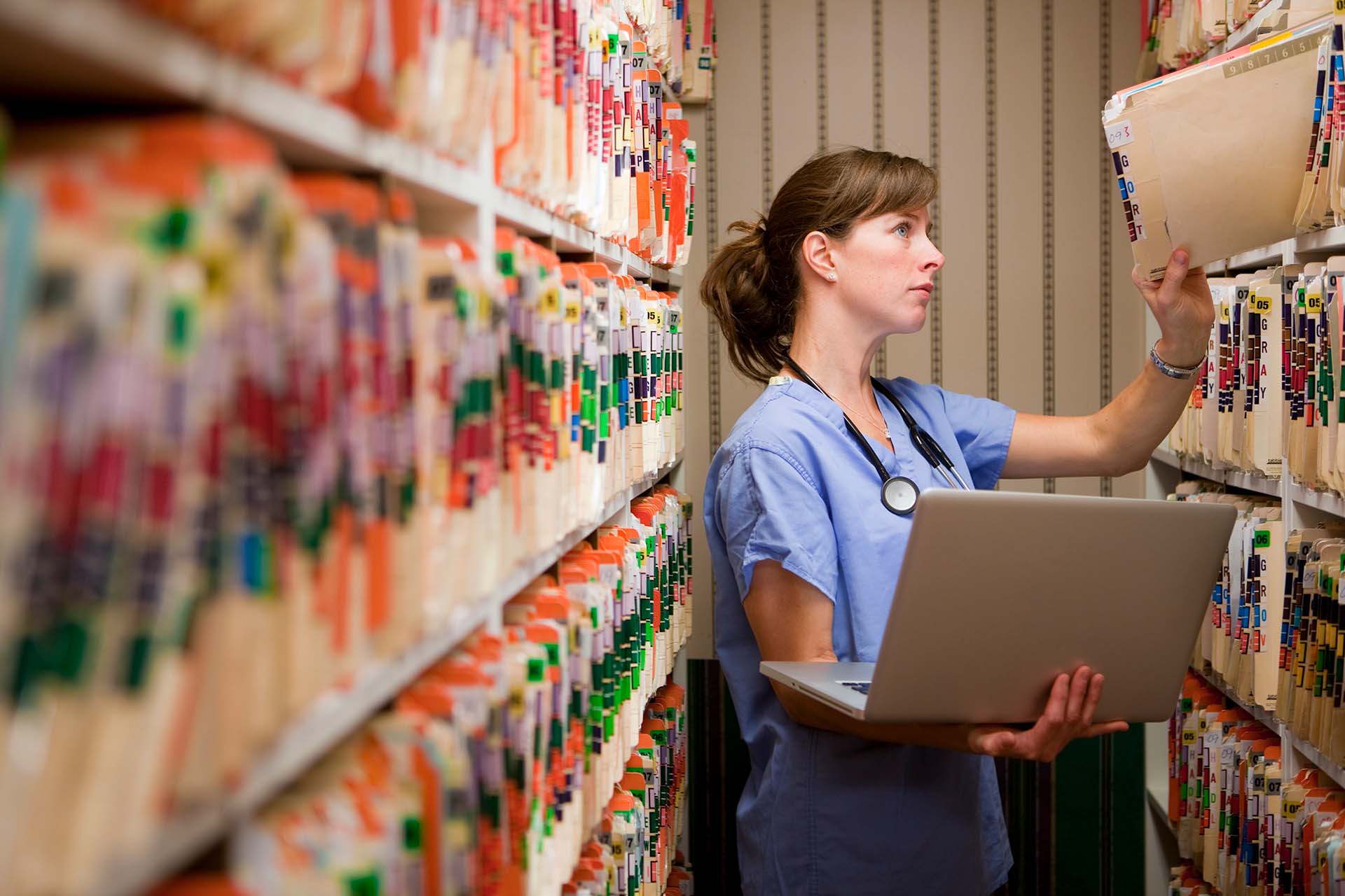 Medical Records New And Old. Nurse comparing computer medical records to old paper records.