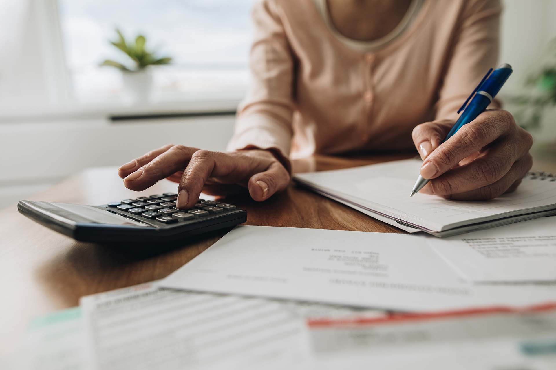 Close Up Of Woman Planning Home Budget And Using Calculator. Close up of unrecognizable woman using calculator while going through bills and home finances.