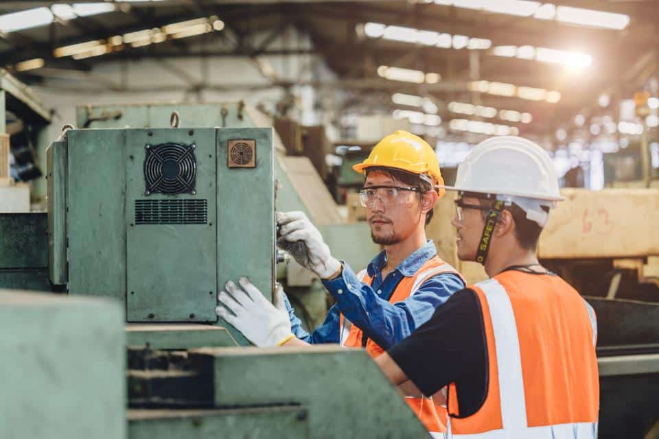 Industry worker working together training young new machine operator staff in metal factory.