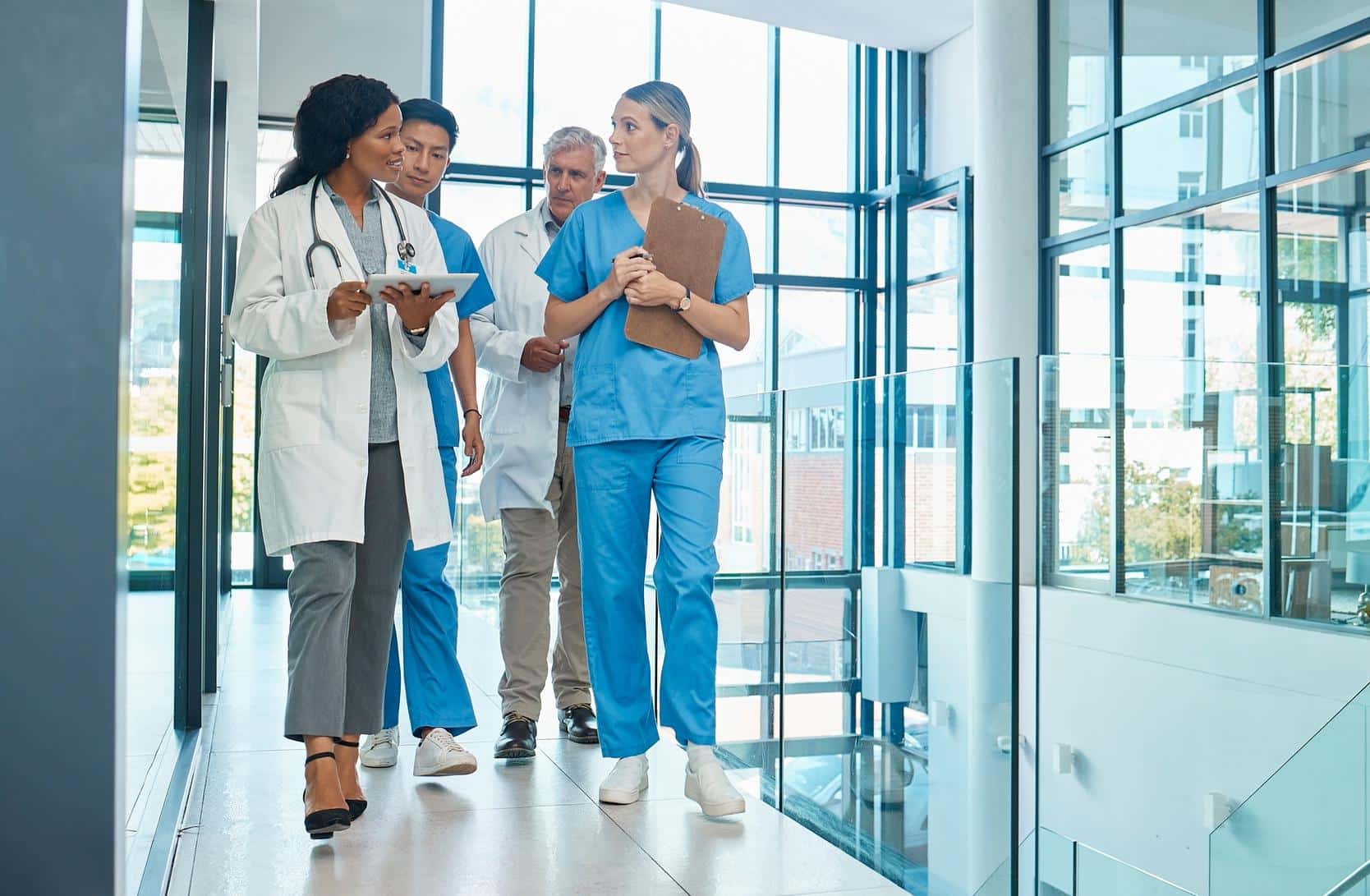 Hospital, doctors and nurses team walking with a tablet for a discussion, planning or research. Diversity men and women healthcare group talking about medical strategy, virus or surgery schedule.